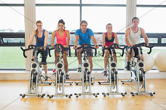 Five determined people working out at spinning class