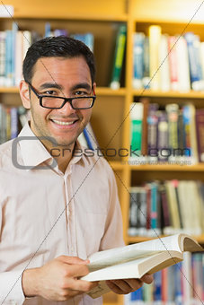 Smiling mature student with book in library