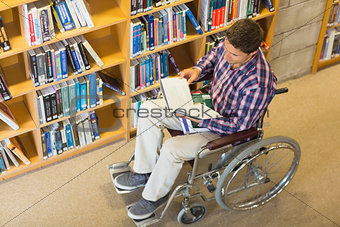 Man in wheelchair reading a book in the library