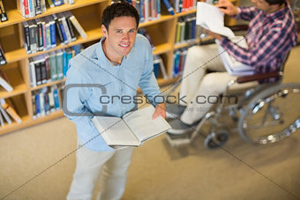 Man by disabled student in wheelchair in the library