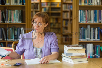 Mature female student studying at desk in the library