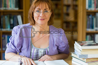 Cmiling mature female student at desk in the library