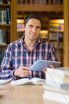 Happy mature student holding tablet PC in the library