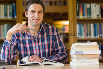 Smiling mature student studying at desk in the library