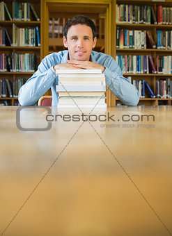 Mature student with stack of books at desk in the library