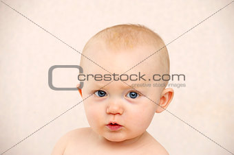 Baby looking at the camera on a peach background