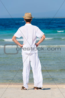 Man in white suit on a tropical beach, back view