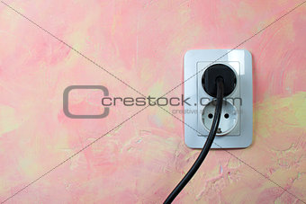 White socket and cable on pink wall. 