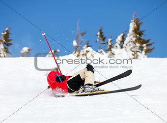 Girl skier falling down white on mountain slope