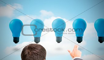 Businessman pointing with two fingers at blue light bulbs
