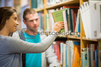 Two young students selecting a book in the library