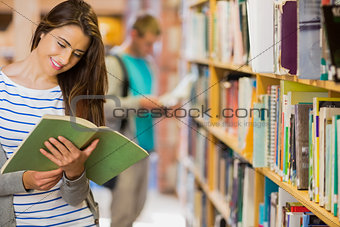 Two young students by bookshelf in the library