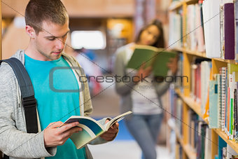 Students reading by bookshelf in the library