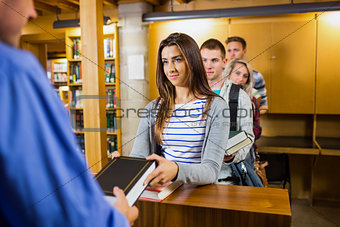 Young students in a row at the library counter