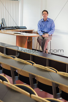 Mlegant male teacher sitting in the lecture hall