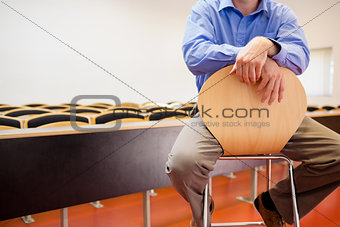Mid section of a teacher on chair in lecture hall