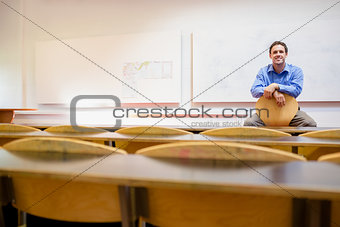 Male teacher sitting on chair in lecture hall