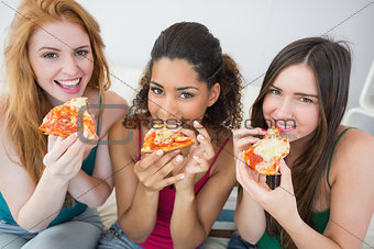 Portrait of happy female friends eating pizza at home