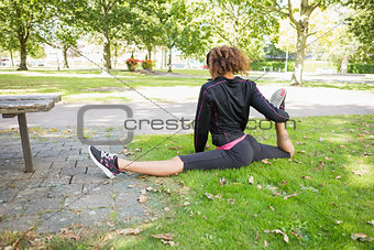 Flexible young woman doing the splits exercise in park