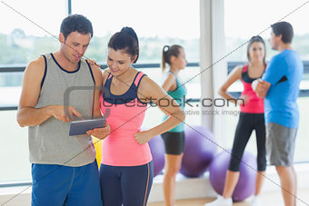Fit couple looking at digital table with friends chatting in background