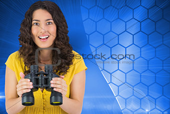 Composite image of smiling young woman holding binoculars