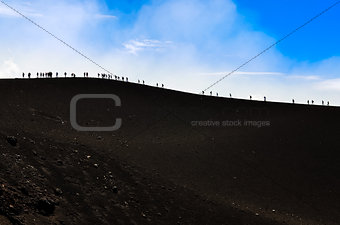 Group of trekkers hiking on a volcano hill