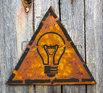 Light Bulb Icon on Rusty Warning Sign.