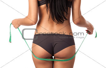 Rear view of a beautiful young woman holding a measure tape