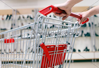 Woman pushing shopping cart in shoe store, close-up