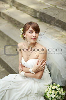 Happy young bride laying on steps.