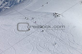 Snowboarders and skiers downhill on off piste slope.