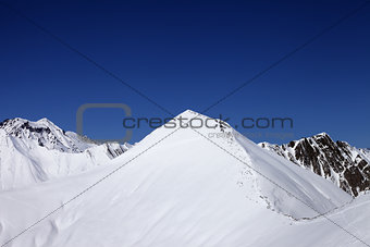 Snowy off-piste slope and blue clear sky at nice winter day