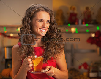 Happy young woman with cup of ginger tea looking on copy space