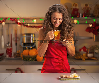 Happy young woman drinking ginger tea in christmas decorated kit