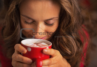 Portrait of happy young woman enjoying cup of hot chocolate with