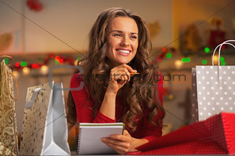 Happy young woman with shopping bags in christmas decorated kitc