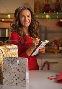 Happy young woman with shopping bags checking list of gifts in c