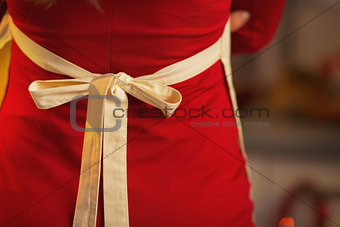 Closeup on young housewife in red dress wearing apron. rear view