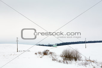Village and power line in snow in winter