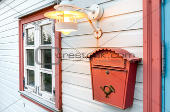 Mail box, window and lamp on a white wooden house 