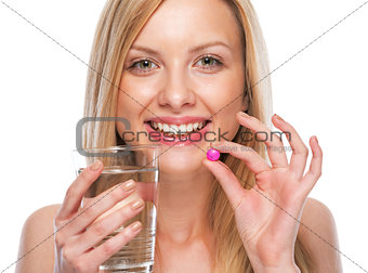 Portrait of happy teenage girl with cup of water and pill