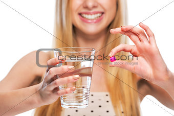 Closeup on smiling teenage girl giving cup of water and pill