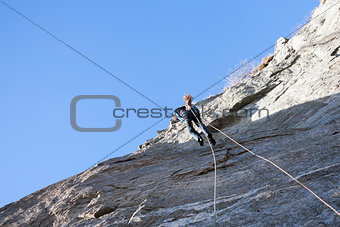 A rock climber abseiling off a climb