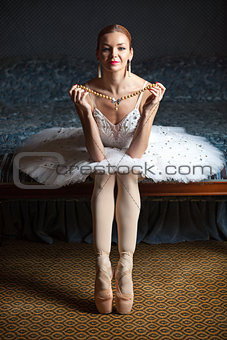 Ballerina holding pearl necklace and smiling