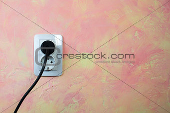 White socket and cable on pink wall. 
