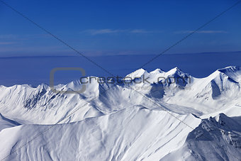 Off-piste snowy slope at sunny day and multicolor blue sky