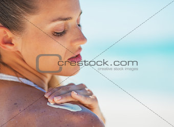Portrait of young woman applying sun screen creme