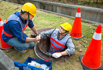 two sewerage workers in the manhole