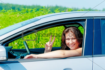 smiling girl driving a car on nature 