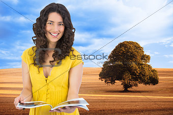 Composite image of cheerful curly haired brunette reading magazine